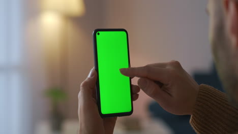 Vista-Más-Cercana-De-La-Pantalla-Verde-De-Un-Teléfono-Celular-Moderno-En-Manos-De-Un-Usuario-Masculino-Que-Se-Desplaza-Por-El-Sitio-De-Navegación-O-Aplicación-De-Tecnología-Moderna