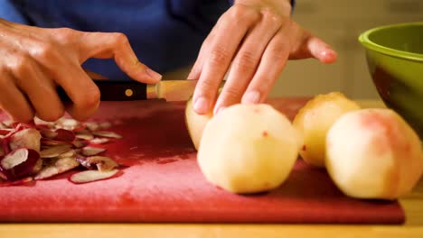 close up hands cutting a peach on a cutting board