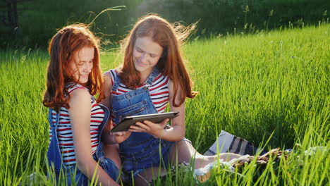 Dos-Hermanas-Gemelas-Usan-Una-Tableta-Al-Aire-Libre