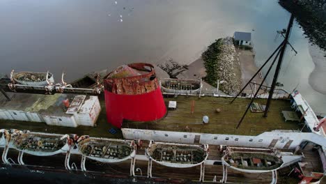 Abandoned-railway-steamer-ship-TSS-Duke-of-Lancaster-beached-near-Mostyn-Docks,-on-the-River-Dee---aerial-pullback