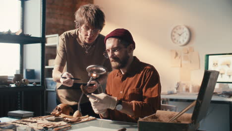 two archaeologists examining and discussing artifacts in laboratory