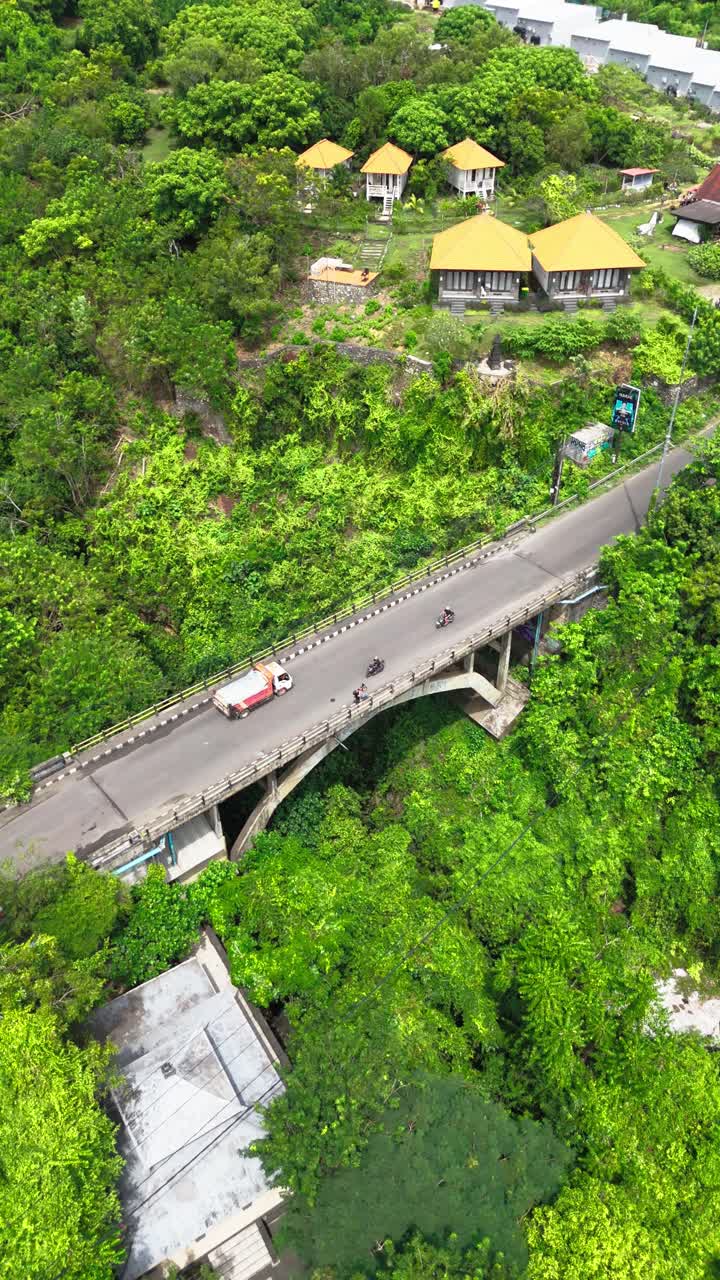 Small bridge over jungle valley near rural village in Indonesia, aerial vertical view