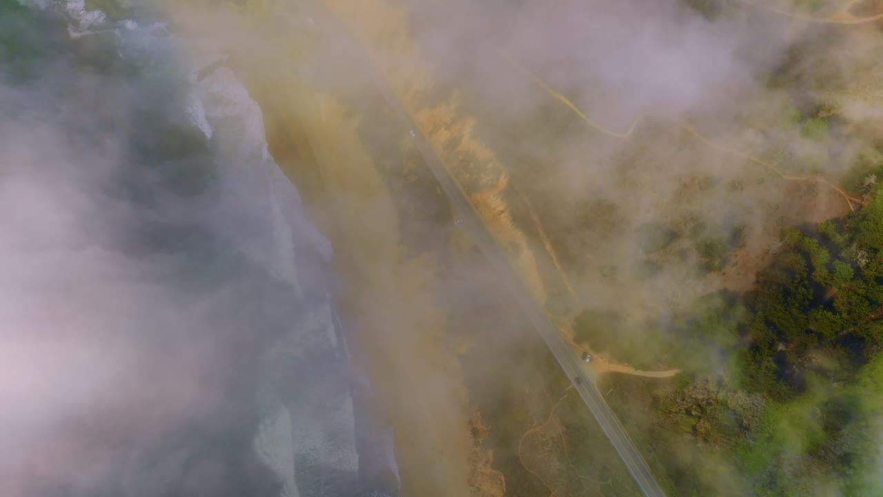 Highway passing through the beautiful sandy coast. Looking down at the Pacific shore through the mist from water.