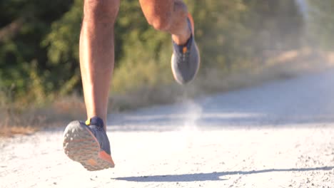 professional runner running fast on dirt path in smooth slow motion tracking from front