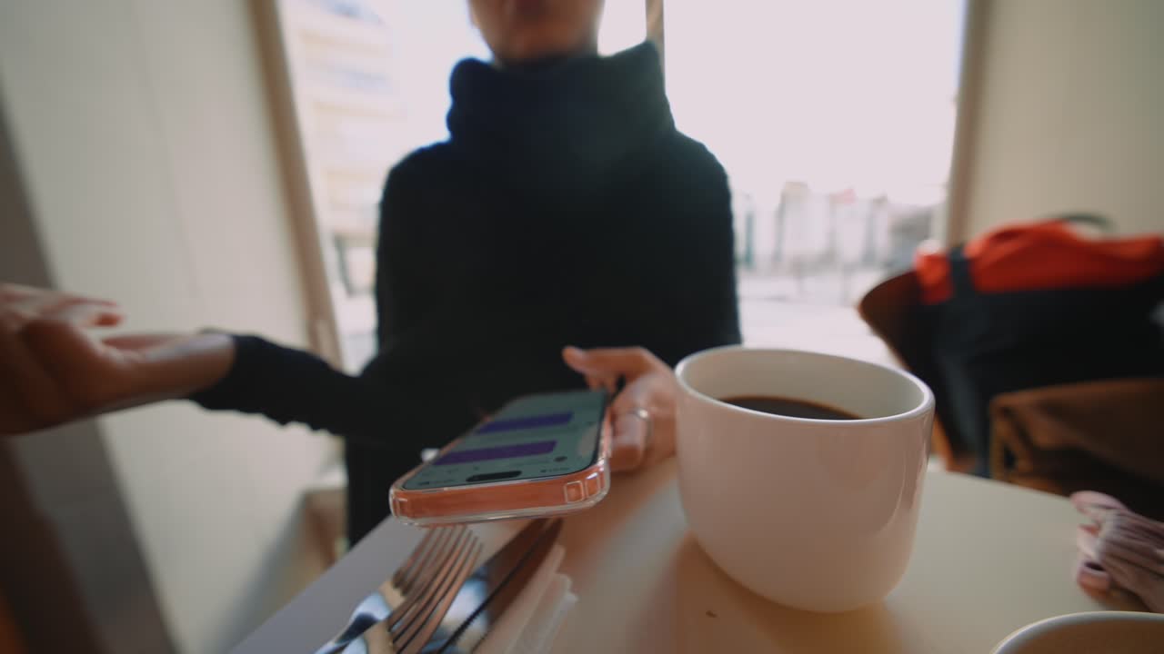 Woman using phone while having coffee