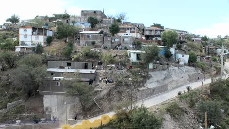 People-walk-around-a-group-of-houses-on-a-hilltop