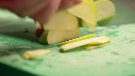 chef slicing fresh green apple on the chopping board in the restaurant kitchen - slow motion