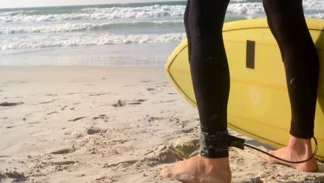 surfista masculino de pie con una tabla de surf en la playa 4k