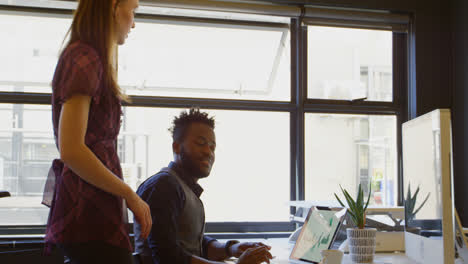 Side-view-of-young-black-businessman-working-on-laptop-at-desk-in-a-modern-office-4k