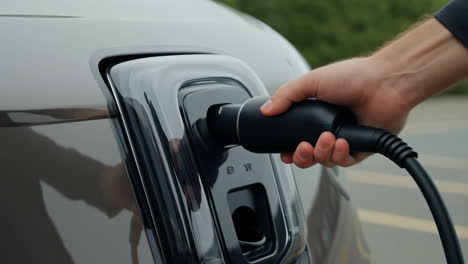 a hand plugs an electric vehicle into a charging station