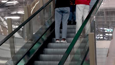 two people ride up an escalator in a building