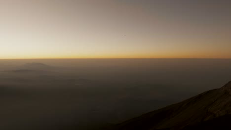 hiker holding flags standing on the summit of acatenango volcano during sunrise in guatemala