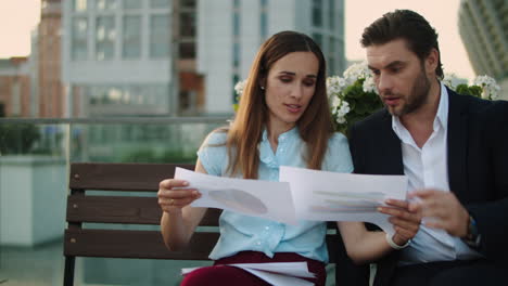 closeup businessman and businesswoman discussing documents on city street