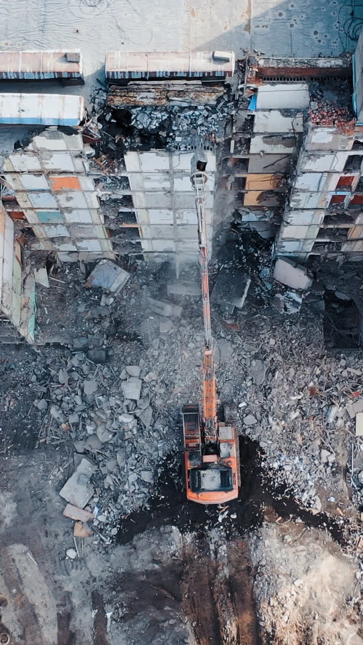 Demolition of building for new construction by excavator bucket. Demolition of the house. City development. View from above. Vertical video