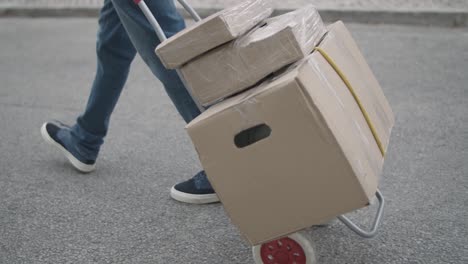 male courier wheeling cart with parcels