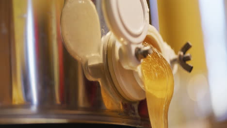 golden thick honey pouring from production tank