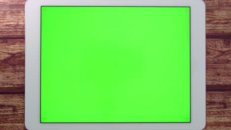 slowly zoom in smart tablet displays green screen chroma key with cross sign on wooden shabby chic table