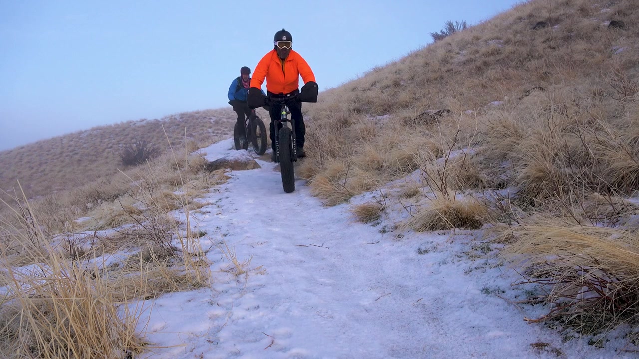 Trois hommes à VTT descendent un sentier enneigé dans les contreforts locaux en hiver