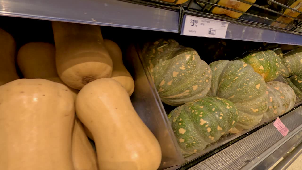 슈퍼마켓의 선반에 버터 스시와 호박이 전시되어 있으며, 부드러운 카메라 움직임과 따뜻한 조명으로 촬영되었습니다.