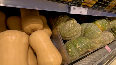 un estante de un supermercado que muestra calabaza y calabazas, capturado con un movimiento suave de la cámara y una iluminación cálida