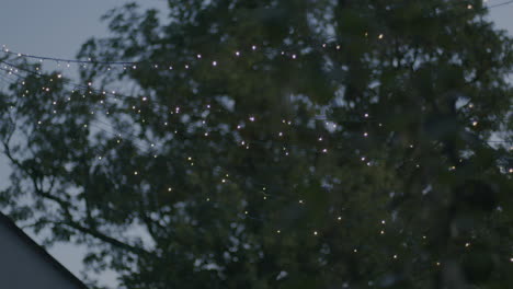 handheld shot of a light string placed outside a house, making star patterns at sunset