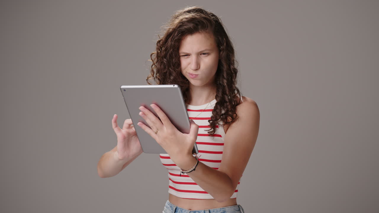 la chica morena usa la tableta, sonríe y asente, mitad del cuerpo en el estudio