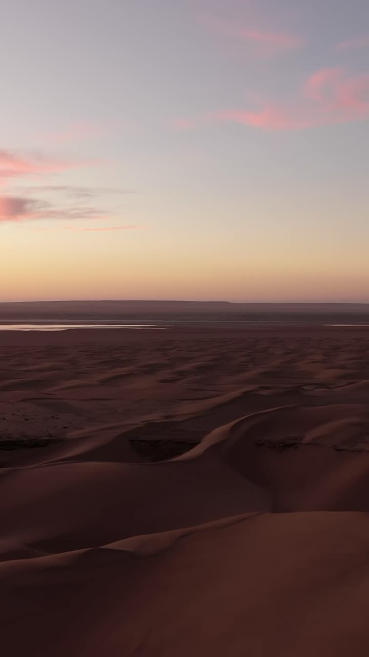 Splendida vista aerea che mostra la vasta distesa di dune di sabbia nel deserto del Sahara. Il sole al tramonto proietta un caldo bagliore sul paesaggio.