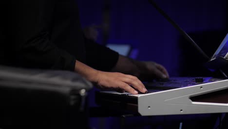 artista de música balcánica tocando sintetizador rápido en un concierto en el interior, cerca de la mano en las teclas