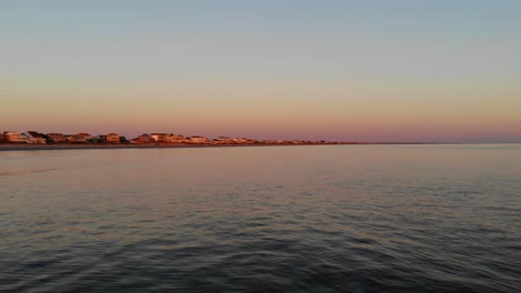 Push-in-cinematic-aerial-drone-flying-low-over-ocean-waves-at-sunset