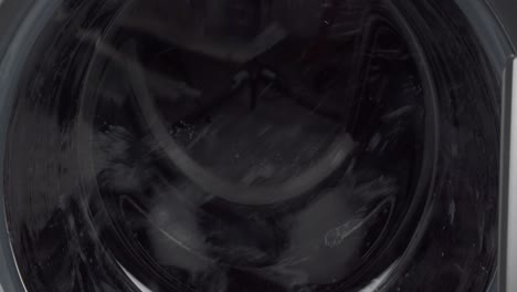 washing machine in motion, rotating slowly with wet laundry, close up