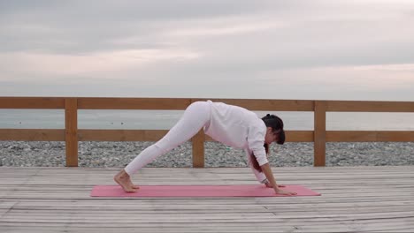 woman practicing yoga poses on a beach deck