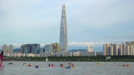 local tourists having fun at han river with water sports activities and view of lotte tower in city of seoul, south korea