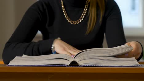 woman reading an open book at a desk