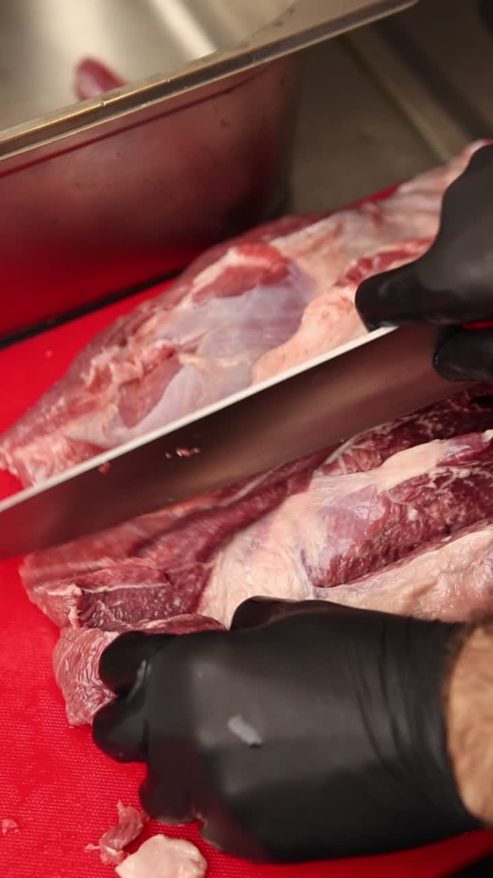Chef che taglia carne cruda su un tagliere rosso