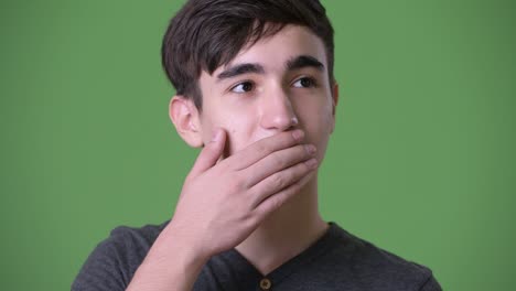 young handsome iranian teenage boy against green background