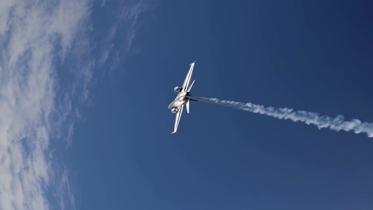 Jet da combattimento F/A-18 Hornet che esegue una manovra aerea con scia di fumo