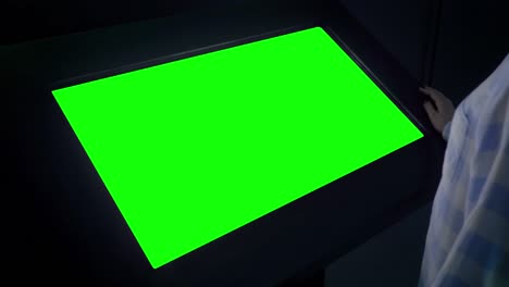 green screen concept - woman looking at blank interactive green display kiosk