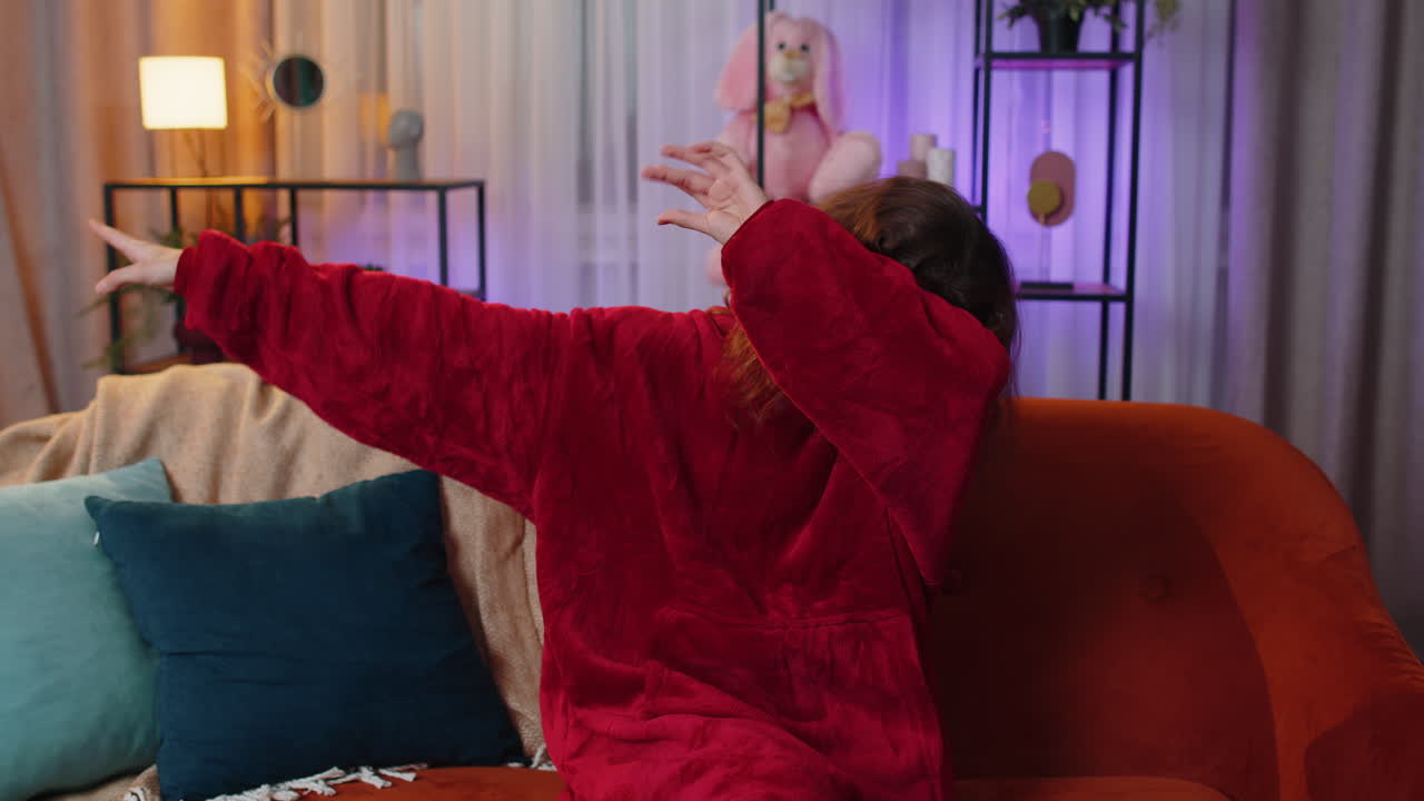 Happy preteen child girl dancing and moving to rhythm making trendy dub dance gesture at modern home