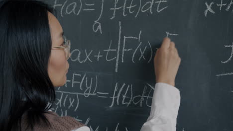 woman writing math equations on a chalkboard