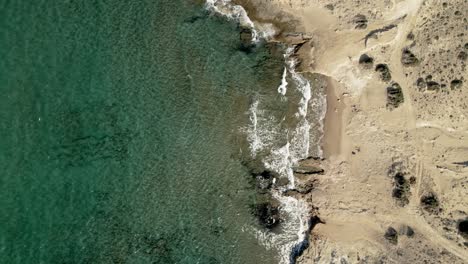 still shot of turquoise blue waves rolling onto sandy mediterranean coastline