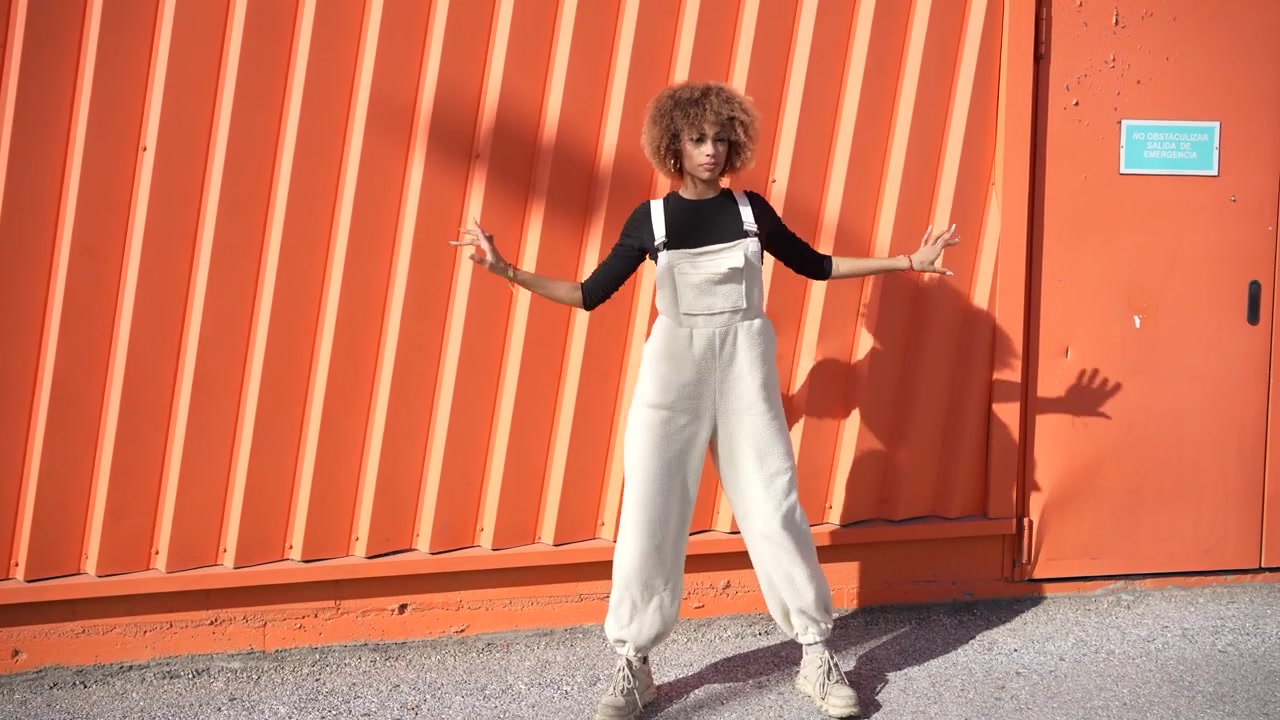A joyful woman energetically dancing against a beautiful and vibrant orange wall