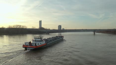 cinematic drone - aerial shot of a ship on the river rhine in bonn with the post tower and the konrad-adenauer bridge at the golden hour, 25p