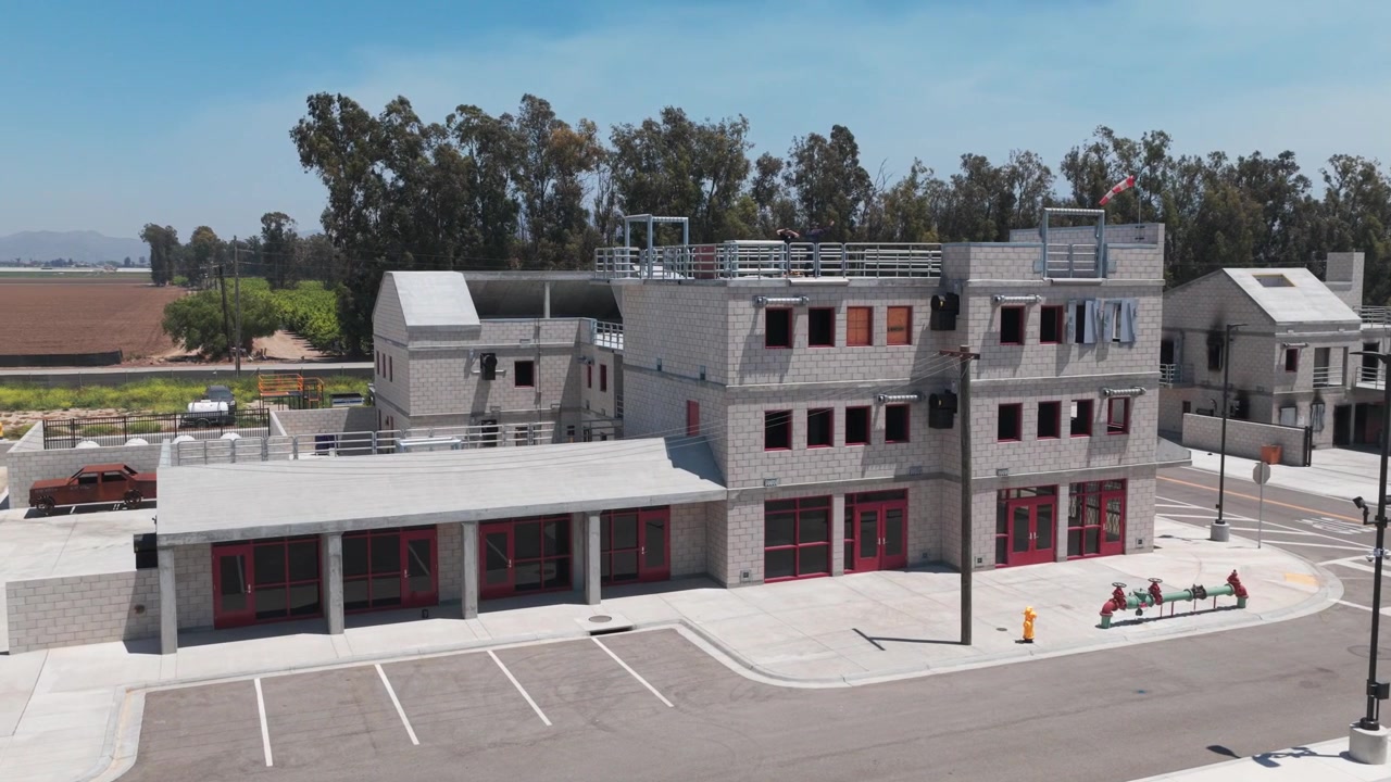 Toma aérea de acercamiento baja de un edificio de hormigón para quemas utilizado para entrenamiento en el centro de entrenamiento del Departamento de Bomberos del Condado de Ventura en Camarillo, California. 4K.