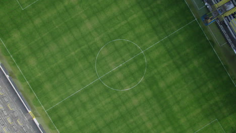 Top-down-drone-raising-shot-of-the-middle-circle-inside-a-football-stadium