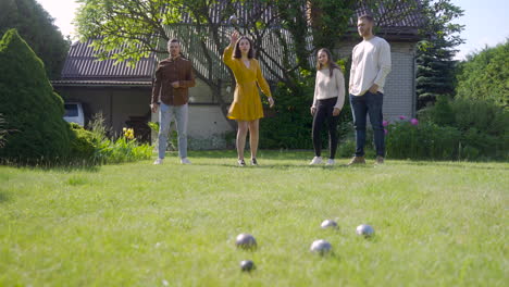 Distant-view-of-caucasian-young-man-throwing-a-petanque-ball-in-the-park-on-a-sunny-day.-Then-his-friend-throws-another-ball