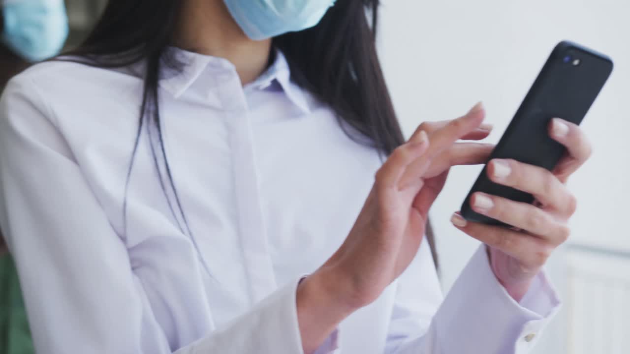 Wanita mengenakan masker menggunakan ponsel pintar.
