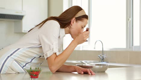 Woman-stirring-and-tasting-something-in-frying-pan-at-the-counter