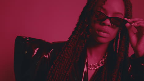 Dramatic-Shot-of-African-Actress-Wearing-Black-Outfit-Posing-in-Front-of-Camera,-Red-Backdrop