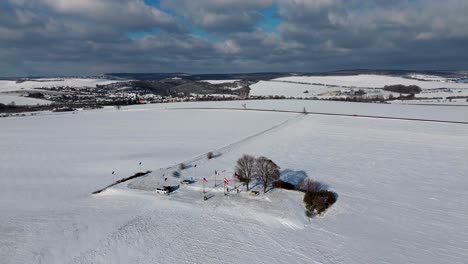 the camera pans away from the top between fields that are all covered in snow with hills in the background