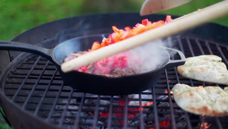 person pouring paprika into a frying pan on a griddle outside while camping